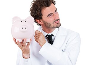 A cosmetic dentist in Mineola holding a piggy bank 