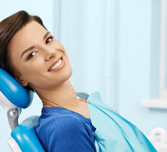 Woman in blue shirt smiling in dental chair