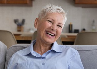 an older woman smiling and enjoying her dentures