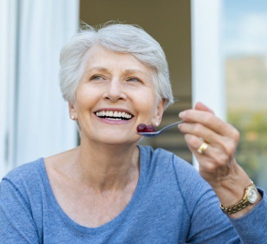 elderly lady eating fruit with a spoon 