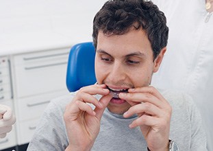 a man putting aligners in his mouth at a dental office