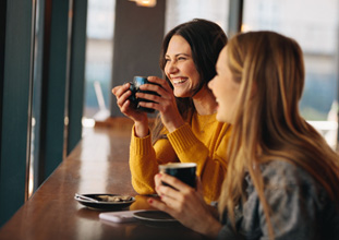 Two friends smiling while drinking coffee