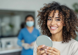 Woman smiling while holding small mirror
