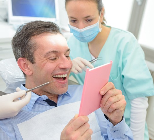 Patient examining his dental bridges in Raleigh