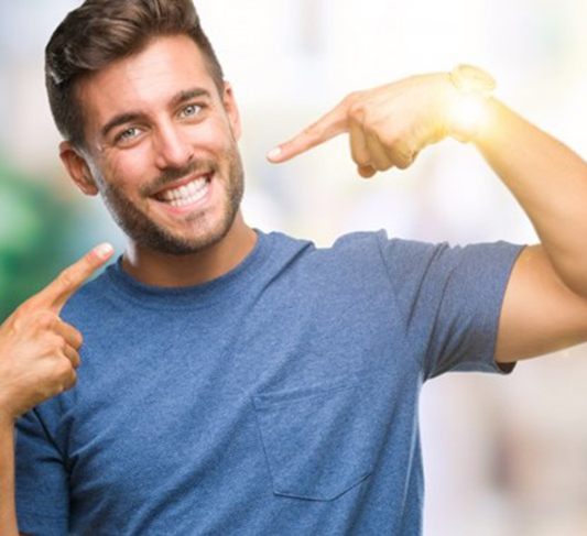 man pointing to his bright smile 