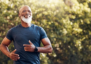 a mature man exercising and smiling with dentures in Raleigh