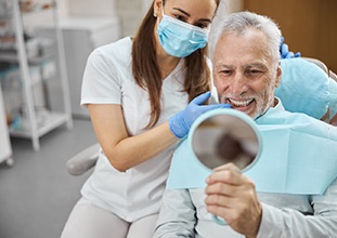 a patient smiling into a handheld mirror