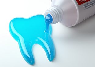 blue toothpaste spilling out into the shape of a tooth 