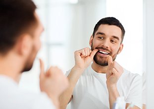 Man flossing to remove plaque from between teeth