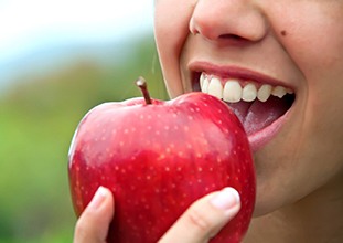 Woman about to take a bite out of an apple