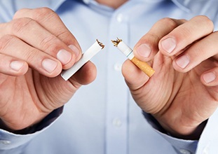 man breaking a cigarette in half 