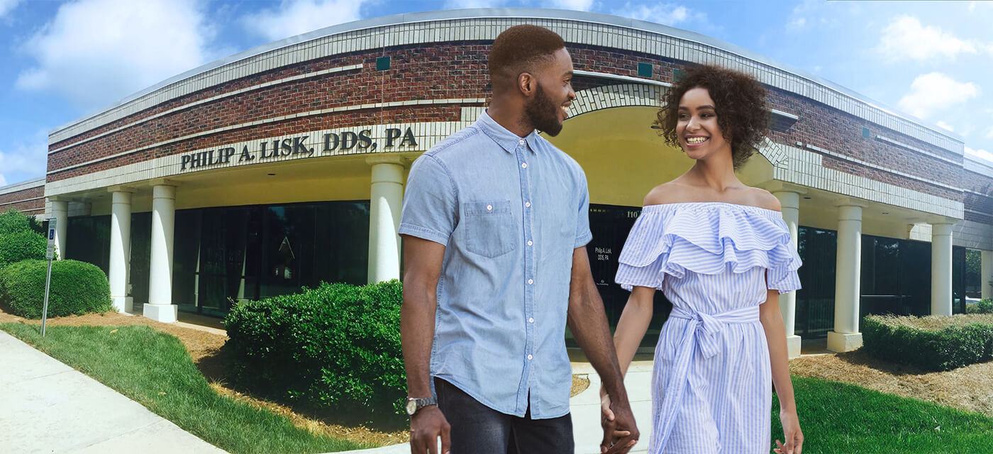 Smiling man and woman holding hands outside of Raleigh dental office