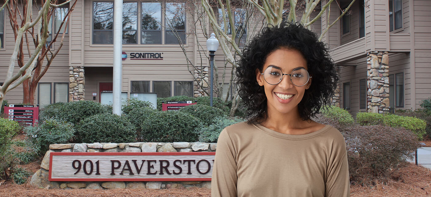 Smiling young woman with glasses outside of Raleigh dental office