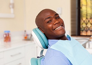 Man in blue shirt smiling in dentist's chair