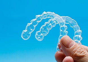 Patient holding up Invisalign in Raleigh