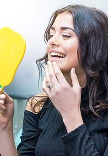 Patient smiling while looking in dental mirror