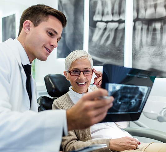 Dentist reviewing dental X-ray with smiling patient
