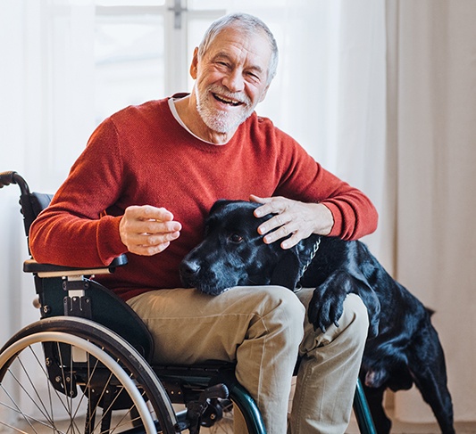 an older man in a wheelchair with a dog in his lap