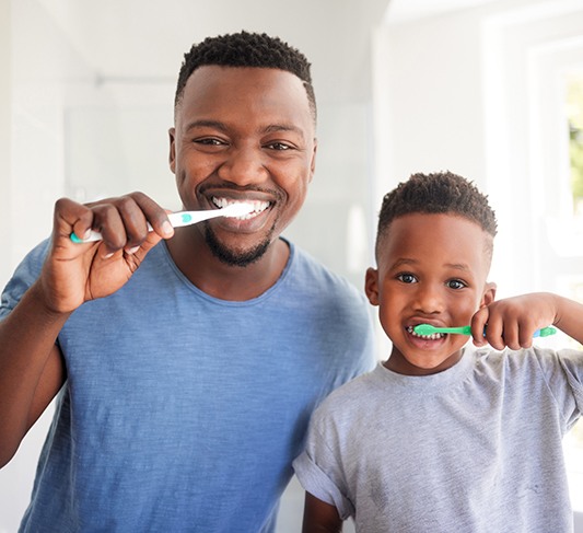 a dad and his son brushing their teeth together
