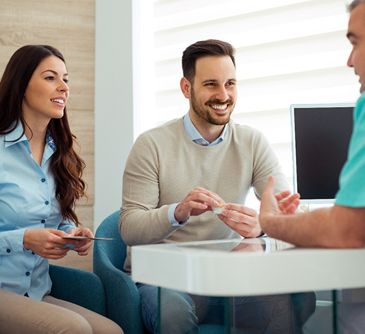 Dentist and couple talking in dental office