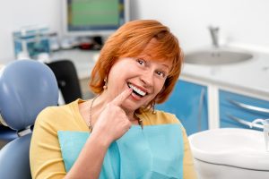 woman smiling pointing at dental implants