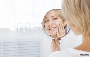 Woman looking at smile in mirror.