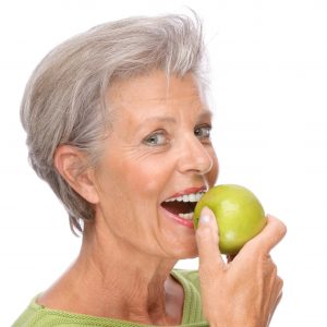 older woman smiling holding apple