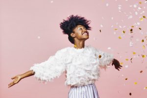 Woman with beautiful teeth smiling and throwing gold glitter 