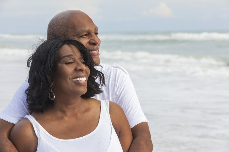 Older couple with dental implants in North Raleigh smiling outside