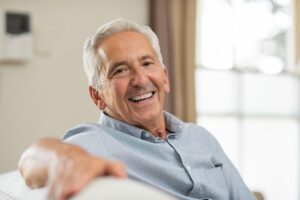 older man smiling and sitting on his couch
