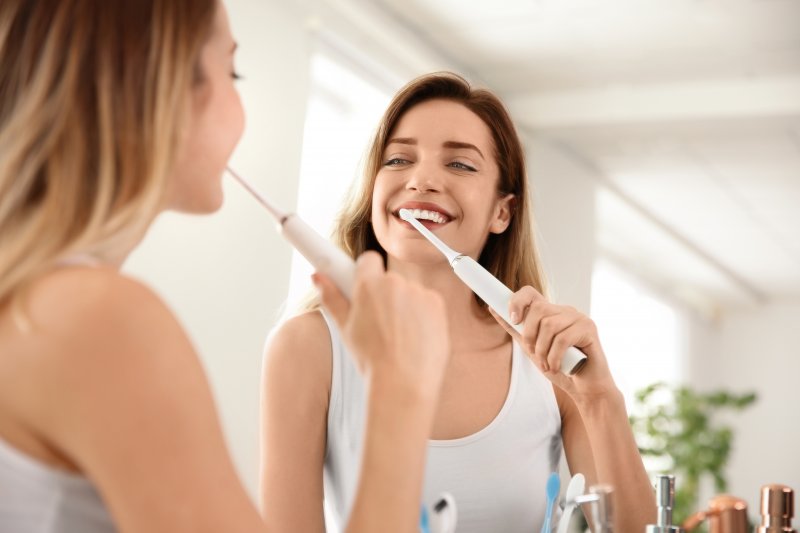 Patient smiling as they brush their dental implants